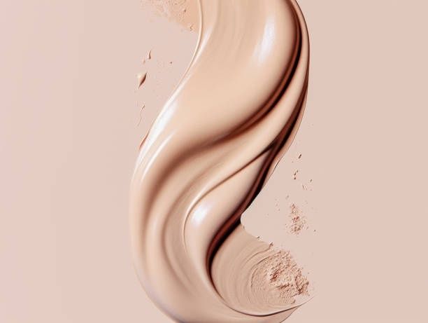 Glanzende, beige foundation uitgesmeerd in golvende lagen